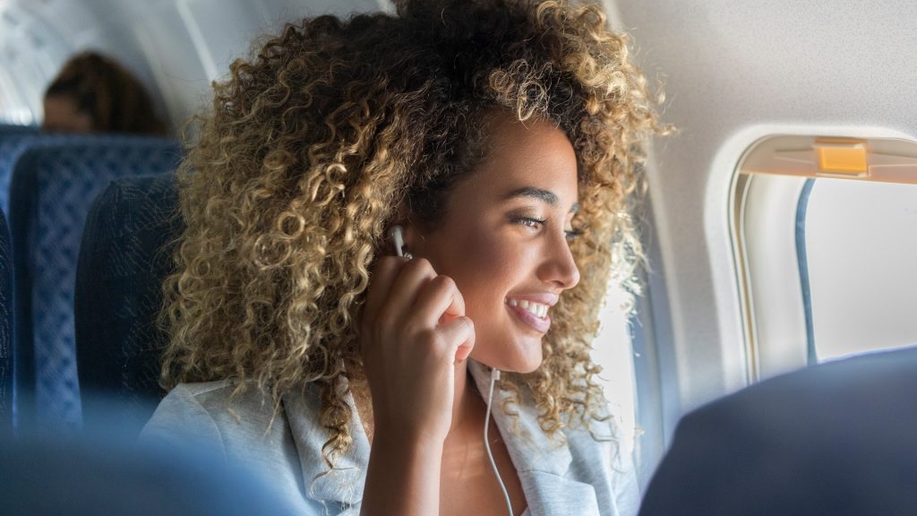 Happy Woman Headphones Airplane Window Seat Istock 1065483408.jpg